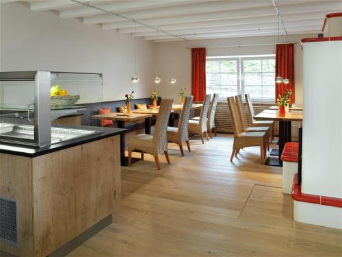 伯森艾科豪森Merker's Hotel & Restaurant Bostalsee的厨房以及带桌椅的用餐室。