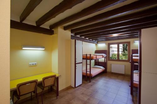 拉莫利纳Alberg La Molina Xanascat的客房设有双层床和桌椅。