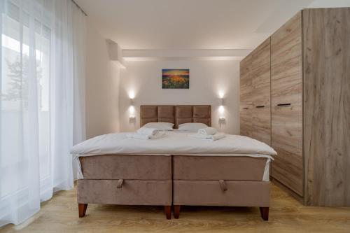 贝尔格莱德M Apartments的一间卧室设有一张大床和一个大型木制橱柜。