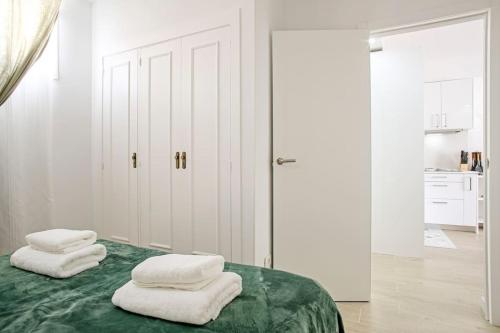 洛斯克里斯蒂亚诺斯Royal Suite Diamantes I With heated pool的一间白色墙壁的卧室和一张带两条白色毛巾的绿色床
