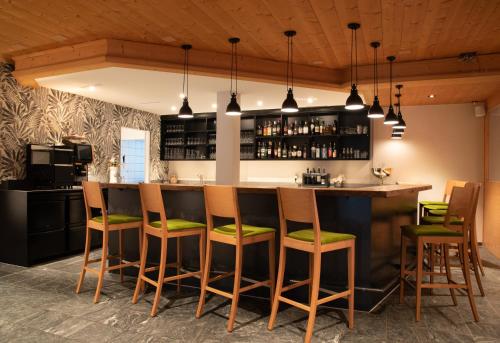 Schiers阿尔皮纳酒店的厨房设有带绿色软垫凳子的酒吧