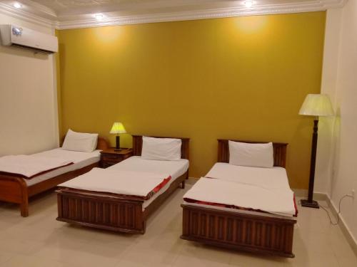 巴哈瓦尔布尔Victoria Guest House的黄色墙壁的客房内的两张床