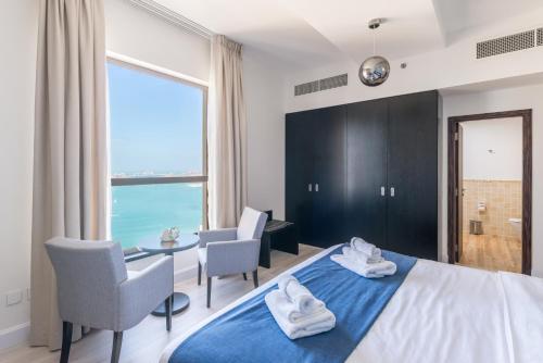 迪拜Luxury JBR Shams - Sea or Marina View - Free 5 star Beach Resorts Access!的卧室配有一张床和一张桌子及椅子