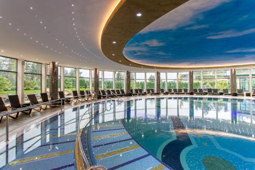 兹拉蒂博尔A Hoteli - Grand&Sky Hotel Tornik的大楼内带椅子的大型游泳池