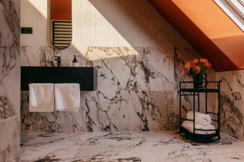 维也纳WELTWIEN Luxury Art Apartments的设有带大理石墙壁、水槽和毛巾的浴室