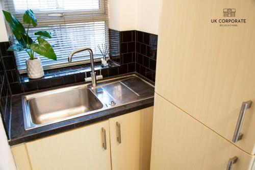 沃灵顿2 bed Apartment by UK Corporate Relocations Ltd的厨房配有不锈钢水槽和窗户