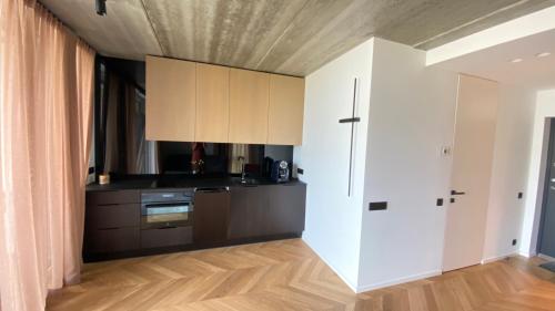 维尔纽斯J. Ralio apartamentai的厨房铺有木地板,配有白色橱柜。