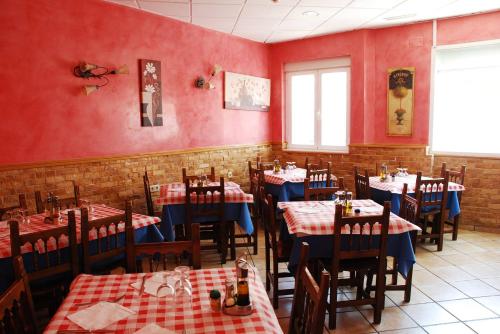 科斯拉达Hostal San Pedro的餐厅拥有红色的墙壁和木桌及椅子