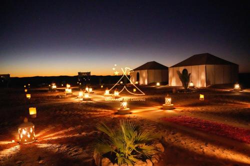 伊尔富德Sahara Desert Camping Merzouga & Erg Chebbi Dunes的一群晚上有灯的小屋