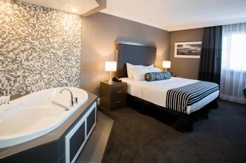 莱斯布里奇Sandman Signature Lethbridge Lodge的酒店客房配有一张床和浴缸。