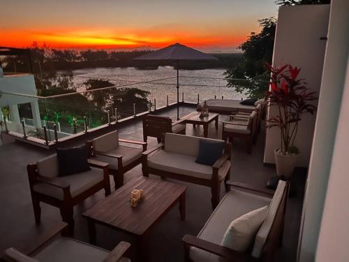 里约热内卢Suítes Luxo Marambaia- Epic House的阳台配有沙发和桌子,享有日落美景。