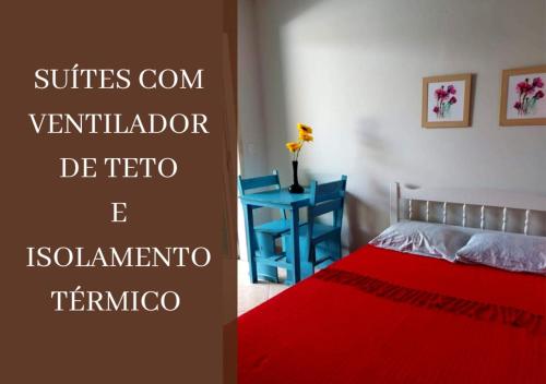 博拉塞亚Pousada Chalé Boracéia的一间卧室配有红色的床和蓝色的桌子