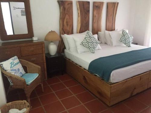 克朗角Reefside Villa的一间卧室配有一张带镜子和椅子的床