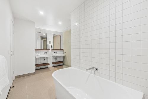 帕金顿Mercure Pakenham的白色的浴室设有浴缸和两个盥洗盆