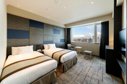 富山HOTEL VISCHIO TOYAMA的酒店客房设有两张床和大窗户。