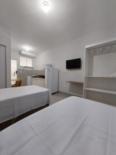乌贝兰迪亚FLAT SABIÁ的白色的客房配有两张床和电视。