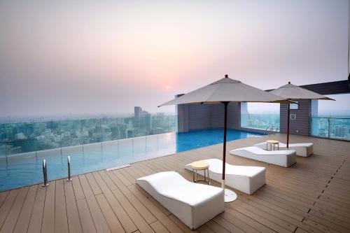 达卡Crowne Plaza Dhaka Gulshan, an IHG Hotel的一个带椅子和遮阳伞的屋顶甲板和游泳池