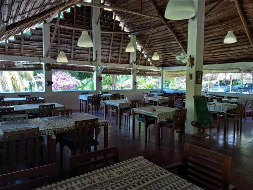 MohéliMoheli Laka Lodge的一间空餐厅,配有桌椅和窗户
