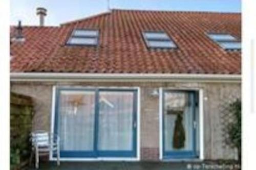 OosterendDe Oostkamer; Eiland appartement naast natuurgebied Boschplaat的屋顶的房子,窗户上有猫