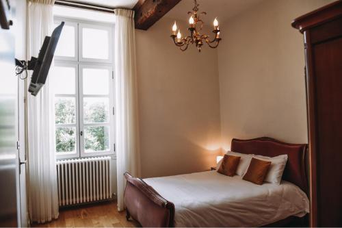 科桑Château de Mons Armagnac的一间卧室配有一张床、一个吊灯和一扇窗户