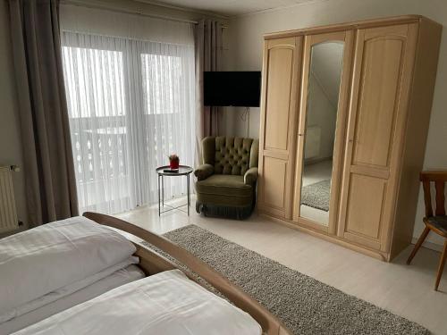 ReuthGasthaus Hubertus的客房设有带镜子和椅子的卧室
