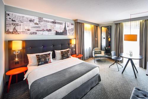 吕贝克Holiday Inn Lübeck, an IHG Hotel的酒店客房设有一张大床和一张书桌。