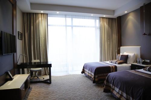 博尔若米博尔若米里卡尼健康和水疗中心酒店 的酒店客房设有两张床、一张书桌和一个窗户。