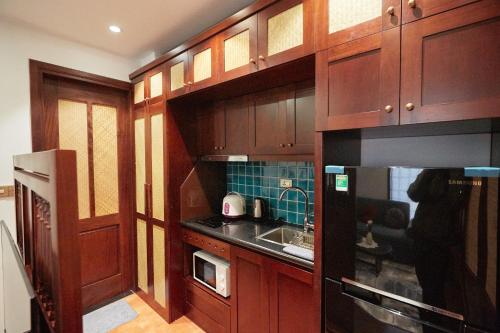 河内Camellia Residence Hanoi的厨房配有木制橱柜、水槽和微波炉