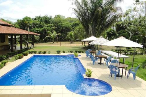 新艾朗Amazônia ParkSuítes的一个带桌椅和遮阳伞的游泳池