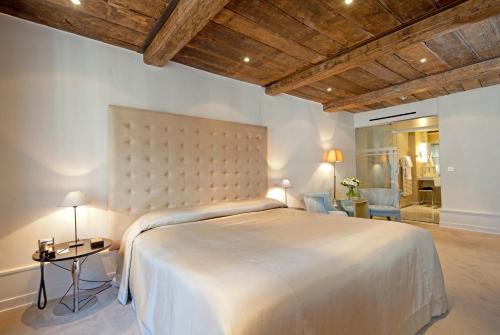 卢森堡Hotel Le Place d'Armes - Relais & Châteaux的卧室配有一张白色大床和木制天花板