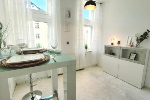 德累斯顿Gemütliches helles Appartement的白色客房,配有带酒杯的桌子