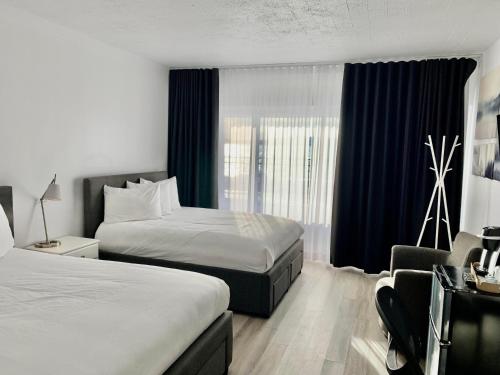 七岛市Hôtel Sept-Îles的酒店客房设有两张床和窗户。