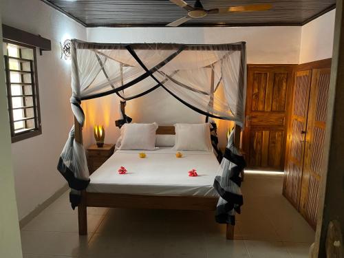 贝岛maison vanilianadia的一间卧室配有带鲜花的天蓬床