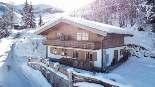 玛丽亚阿尔姆Ski-in & Ski-out out Chalet Maria with amazing mountain view的雪中的一个小木屋,阳光照耀