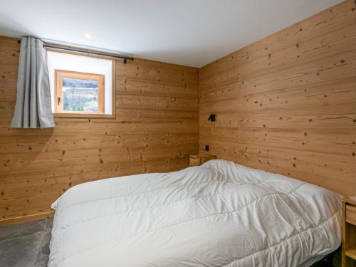 拉克吕萨Appartement La Clusaz, 2 pièces, 4 personnes - FR-1-437-89的卧室设有木墙和白色的床。