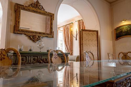 佩达索Dimora Villa Ricci的一间设有玻璃桌和镜子的用餐室