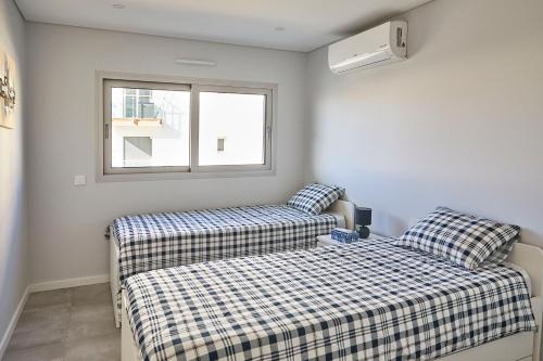 蒙蒂戈杜Nice apartment near the beach - Monte Gordo的一间卧室设有两张床和窗户。