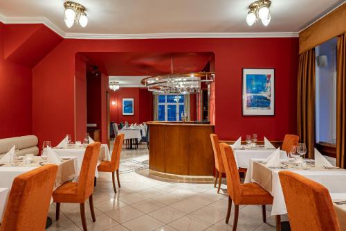 玛丽亚温泉Spa & Wellness Hotel Silva的一间设有白色桌椅和红色墙壁的餐厅