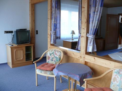 Hemfurth-Edersee多恩罗森索瓦尔德霍特尔酒店的一间设有两把椅子、一张桌子和一台电视的房间