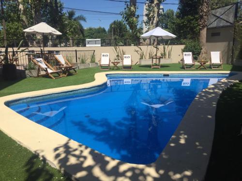 蒂格雷RIO TIGRE HOTEL的庭院内的游泳池,配有椅子和遮阳伞