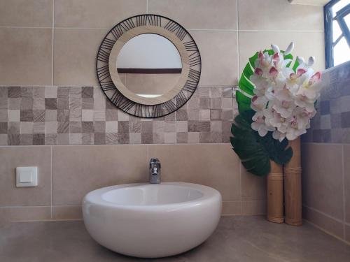 PiraeO'hale Perry的浴室设有水槽、镜子和鲜花