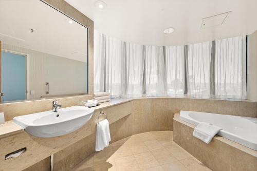 黄金海岸冲浪者天堂皇冠假日酒店的一间带水槽、浴缸和镜子的浴室