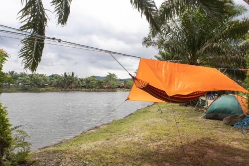 金宝Sahom Valley Resort - Agro & Eco Park的湖畔帐篷上的橙色雨伞