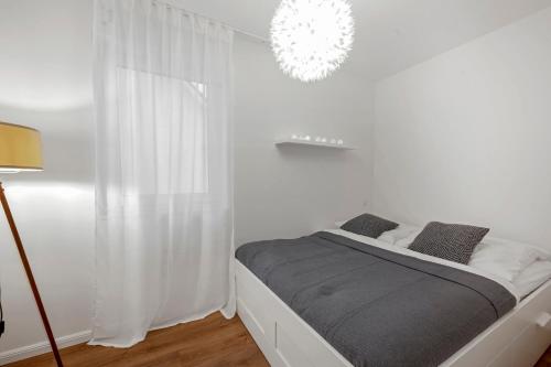 奥尔登堡Nadorst Residenz的白色卧室配有一张床和一个吊灯