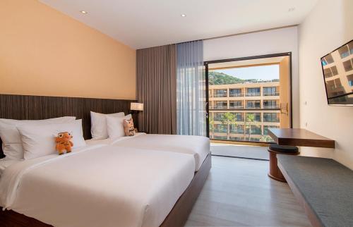 卡塔海滩Pamookkoo的一间设有大床和窗户的酒店客房