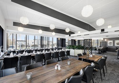 海宁奥斯特吉艾德斯酒店的餐厅设有木桌、椅子和窗户。