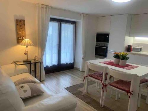 平佐洛Pinzolo, grazioso appartamento, wellness a 100 metri的一间带白色桌子的客厅和一间厨房
