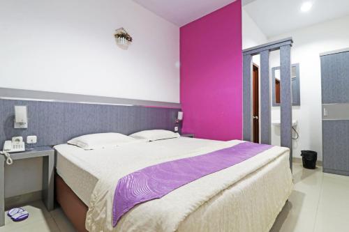 北干巴鲁Paus Guest House Pekanbaru的一间卧室配有一张带粉红色墙壁的大床