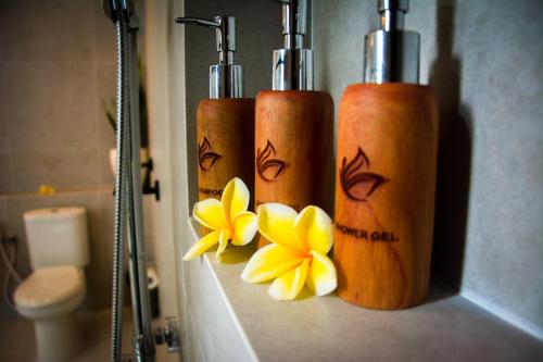 塞米亚克The Kon's Villa Bali Seminyak的浴室内3个带鲜花的木瓶子