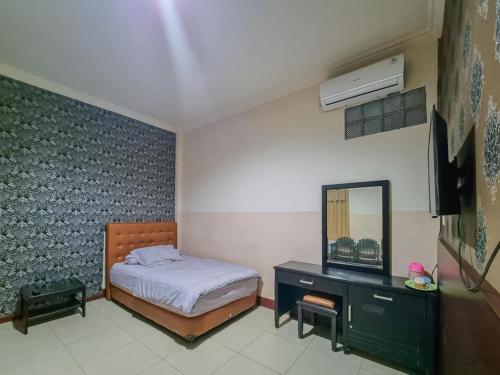 帕朗卡拉亚Hotel Halmahera Palangkaraya Mitra RedDoorz的一间卧室配有一张床、梳妆台和镜子